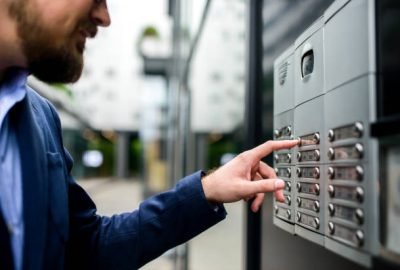 Man pushing the button and talking on the intercom in front of the apartment
